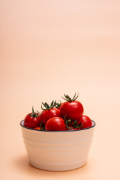 橘色背景上碗里装满圣女果、小番茄