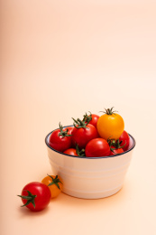 橘色背景上碗里装满圣女果、小番茄