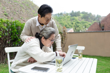 一对亚洲的老年夫妻在椅子上使用笔记本电脑