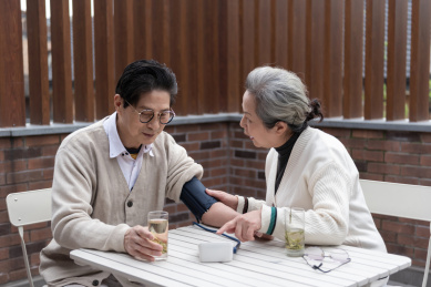 一对亚洲的老年夫妻在椅子上测量血压