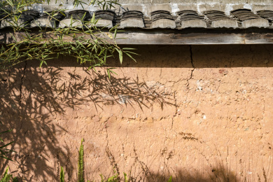 屋檐下的黄色泥土墙及投射在上面的竹影