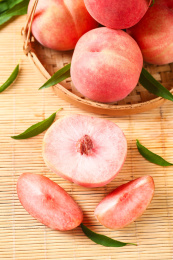 竹垫子上放着一筐新鲜桃子和桃子果肉