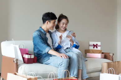 一对年轻的亚洲情侣在沙发上互送礼物