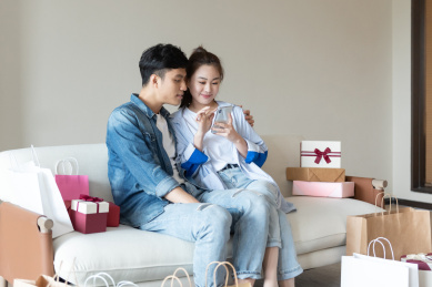 一对年轻的亚洲情侣在沙发上互送礼物