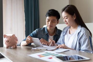 一对年轻的亚洲情侣在坐在地毯上做规划