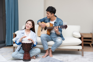 一对年轻的亚洲情侣正正在弹琴唱歌