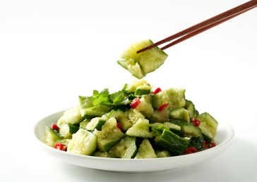 白色背景上筷子夹起的凉拌黄瓜