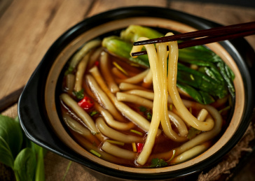 木色背景上筷子夹起的南瓜土豆粉