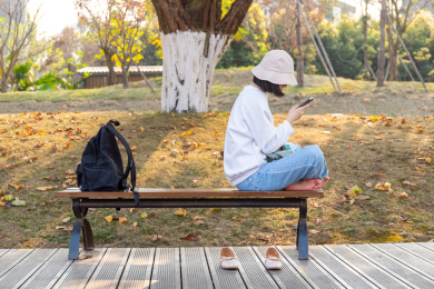 戴帽子女孩盘腿坐着玩手机