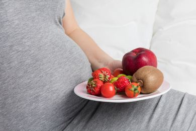 孕妇手拿着一碟新鲜水果