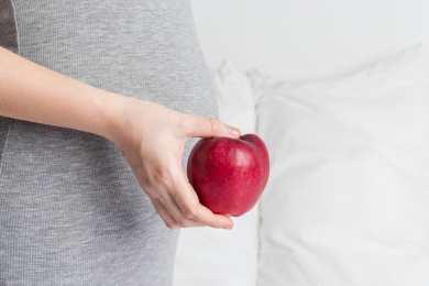 孕妇手拿着一只红色的苹果