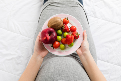 孕妇手拿着一碟新鲜水果