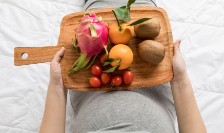 孕妇双手捧着一盘新鲜水果