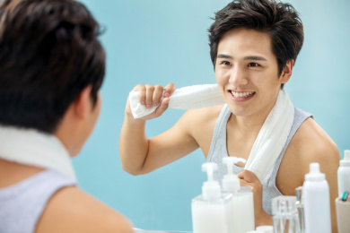 快乐的年轻男人拿着毛巾照镜子