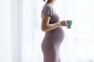 一名年轻孕妇在窗边喝茶