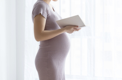一名年轻孕妇在窗边看书