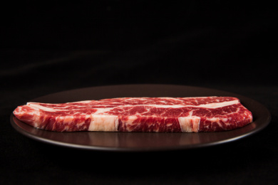 深色背景下放在黑色岩石盘子上的雪花生牛排