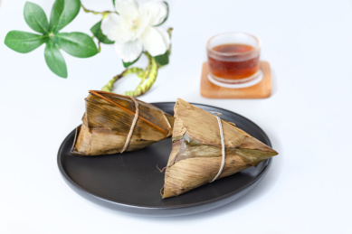 黑餐盘装着的棕子及一杯红茶