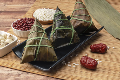 放在木背景上盛在黑色盘子里的粽子