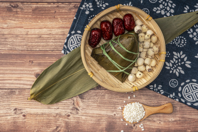 放在木背景上盛在竹筐里的粽子、莲子和红枣