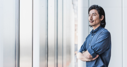 自信的成功人士双手环胸站在窗边