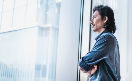 自信的成功人士双手环胸站在窗边