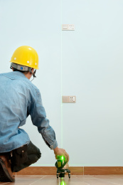 戴安全帽的装修工人用红外线水平仪测量