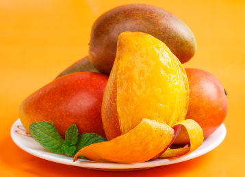 彩色背景上放着一盘贵妃芒果和贵妃芒果果肉