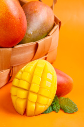 彩色背景上放着一筐贵妃芒果和贵妃芒果果肉