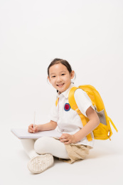 坐在白色背景前在作业本书上写的中国女孩