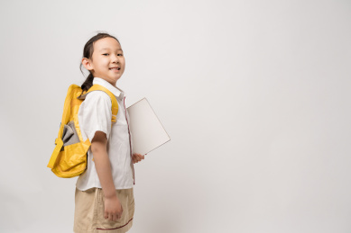 站在白色背景拿着作业本的中国女孩