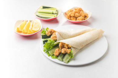 白色桌面上放着一些鸡米花卷饼和小菜