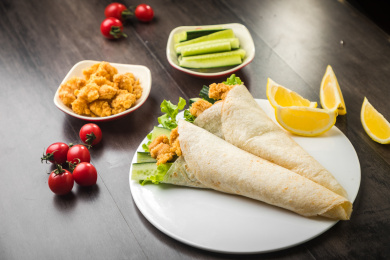 暗色木纹桌面上放着一些墨西哥鸡卷饼和小菜