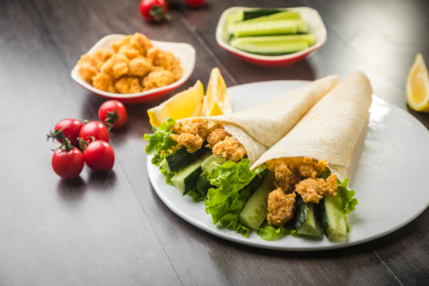 暗色木纹桌面上放着一些墨西哥鸡卷饼和小菜