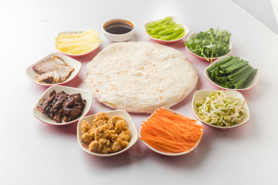 白色桌面上放着一些卷饼和小菜