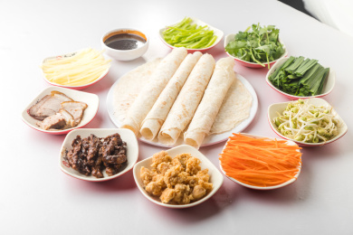 白色桌面上放着一些卷饼和小菜