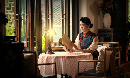 穿着中国传统服装的女人坐在桌子前读着书信