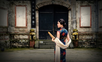 一位穿着旗袍站在一个古宅门前的女人背影