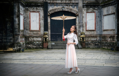 穿着民国时期服装的女人站在一座古宅门前