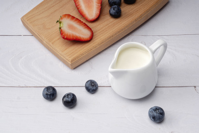 放在白色牛奶杯里的牛奶和木板上的草莓蓝莓
