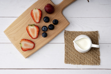 放在白色牛奶杯里的牛奶和木板上的草莓蓝莓