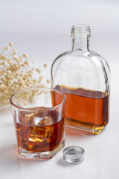 一杯加有冰块的洋酒与扁平酒瓶特写