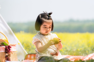 夏天坐在油菜花田边玩耍的女童