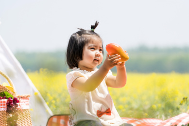 夏天坐在油菜花田边玩耍的女童