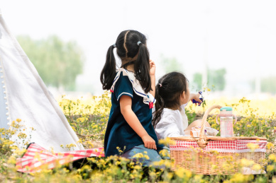 夏天两个在油菜花田边野餐的女孩