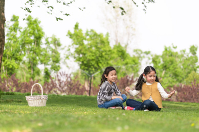 两个坐在树下玩拍手游戏的女孩