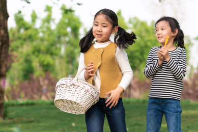 两个在树下玩吹泡泡游戏的女孩