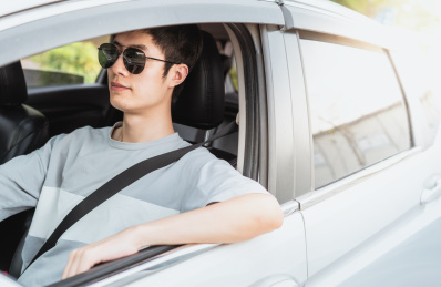 戴着墨镜的男性司机靠着车窗休息