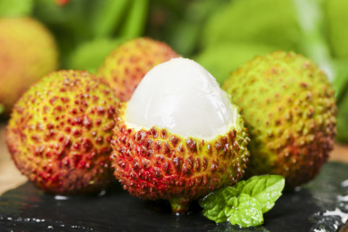 黑底上放着一堆新鲜妃子笑和妃子笑果肉 