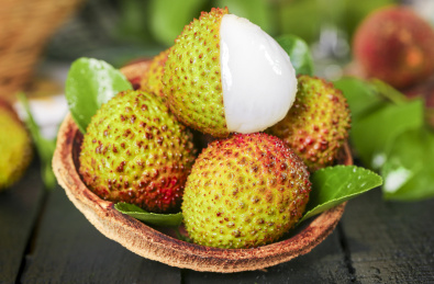 黑底上放着一篮新鲜荔枝和荔枝果肉  